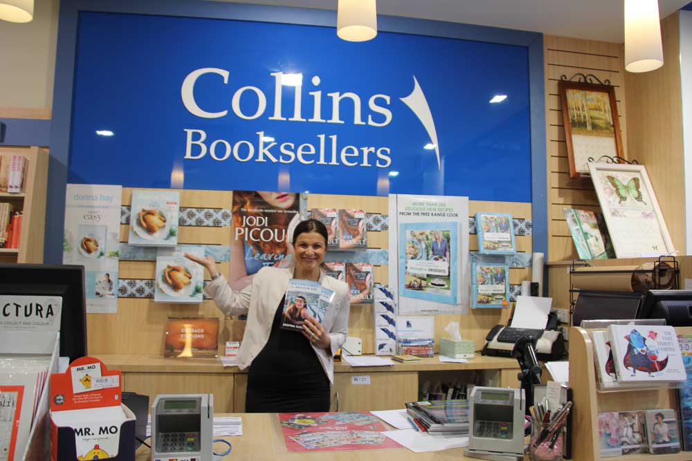 Despina Karatzias holding a book inside Collins Bookseller store.