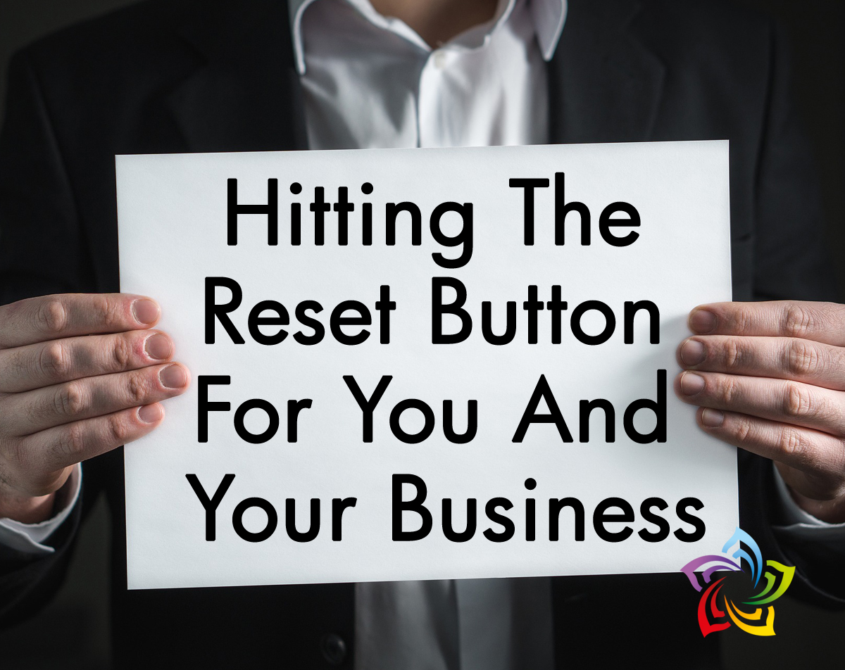 A man holding a paper that says 'Hitting The Reset Button For You and Your Business'