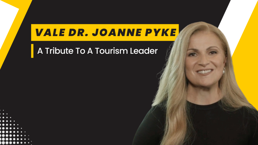 Smiling woman in black attire with text overlay: Vale Dr. Joanne Pyke - A Tribute to a Tourism Leader.