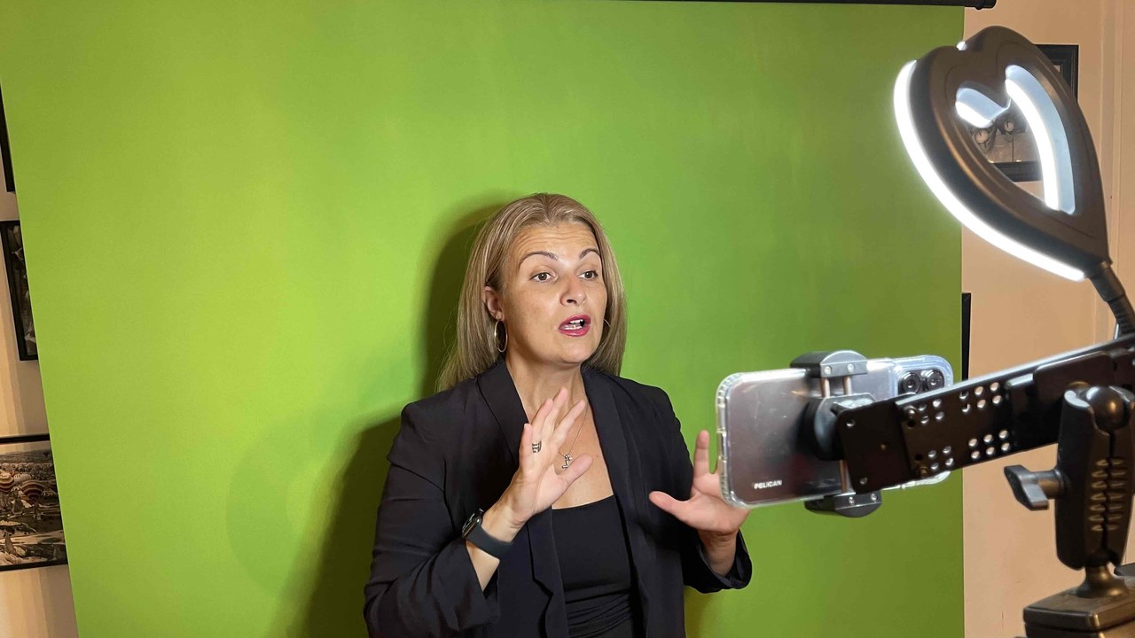 Despina Karatzias speaking to a phone on a tripod with a ring light and green screen while batch recording videos for a 30-day marketing challenge