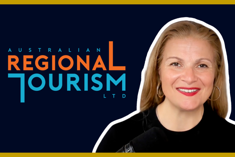 Smiling woman with red lipstick and hoop earrings in front of the Australian Regional Tourism Ltd logo.